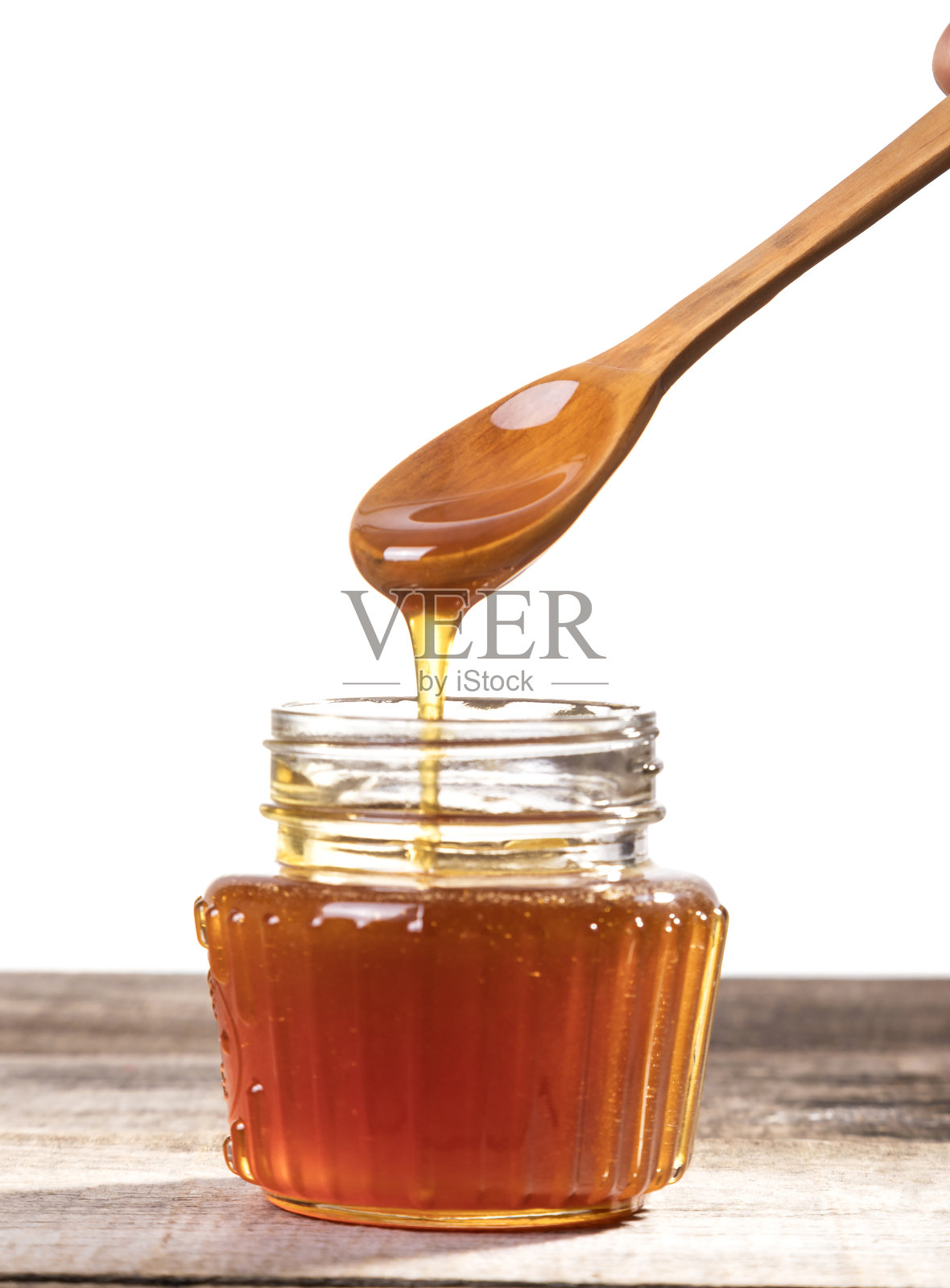 蜂蜜滴进玻璃瓶。照片摄影图片