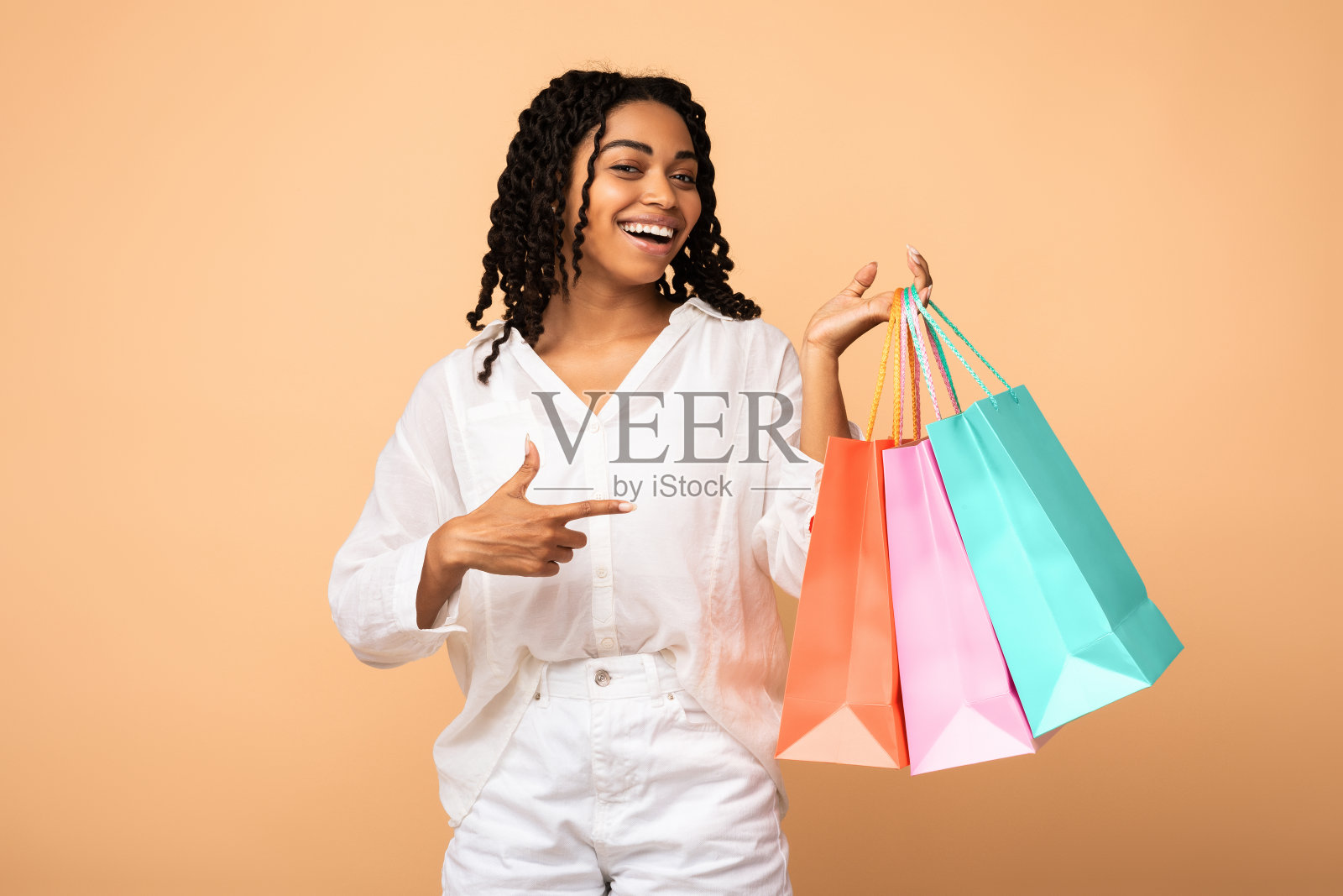 非洲购物狂女孩展示购物袋站在米色背景照片摄影图片