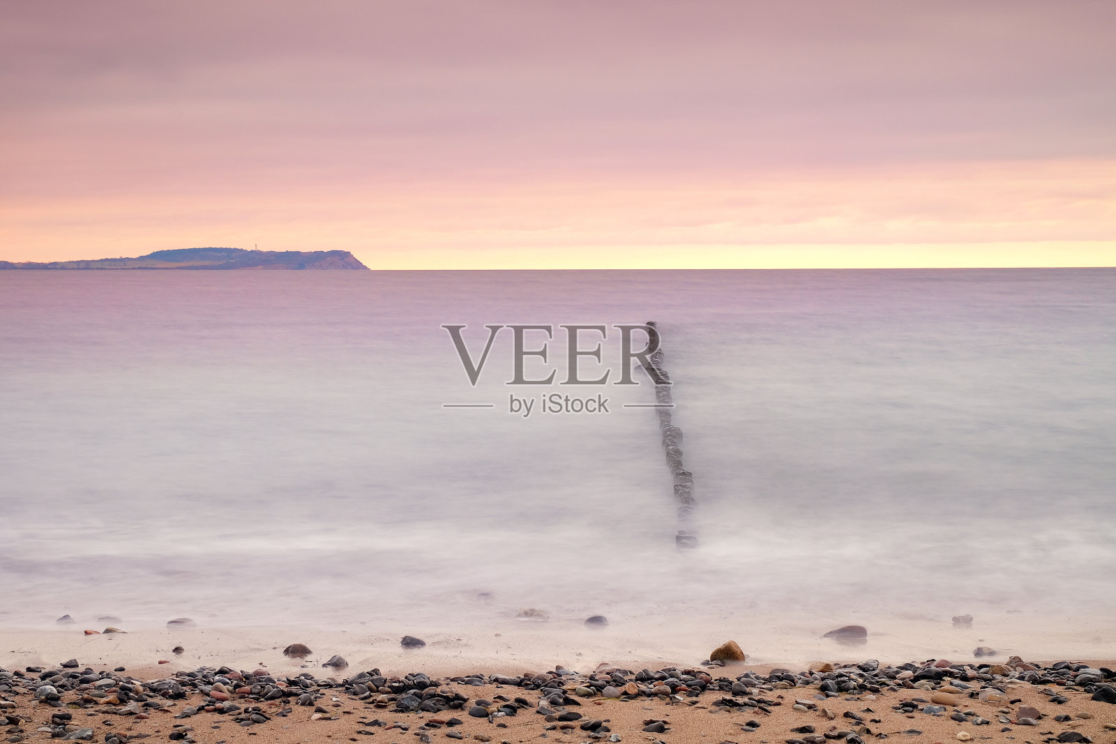 日落在平静的水面上与防波堤的观点照片摄影图片