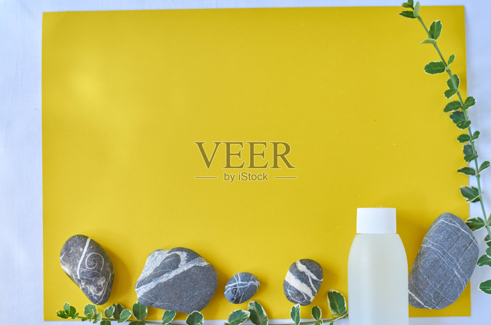 海上的石头,石子。化妆品模型的蓝色瓶子。平放俯视图拷贝空间。品牌产品，美容背景。天然护肤美容产品概念上的黄色背景照片摄影图片