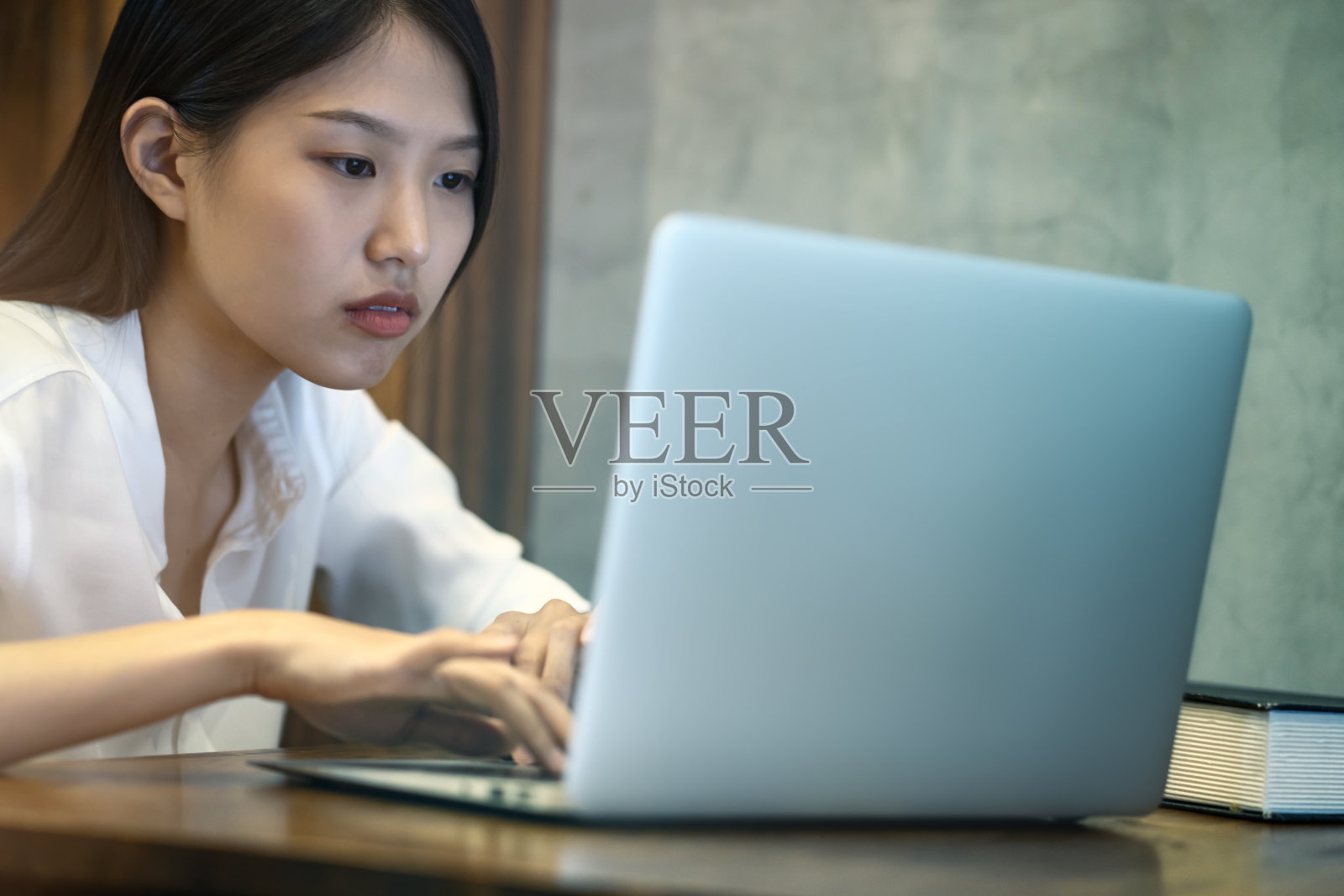 压力很大的亚洲女性工作到很晚，注意力集中在办公室的木桌上用笔记本电脑工作照片摄影图片