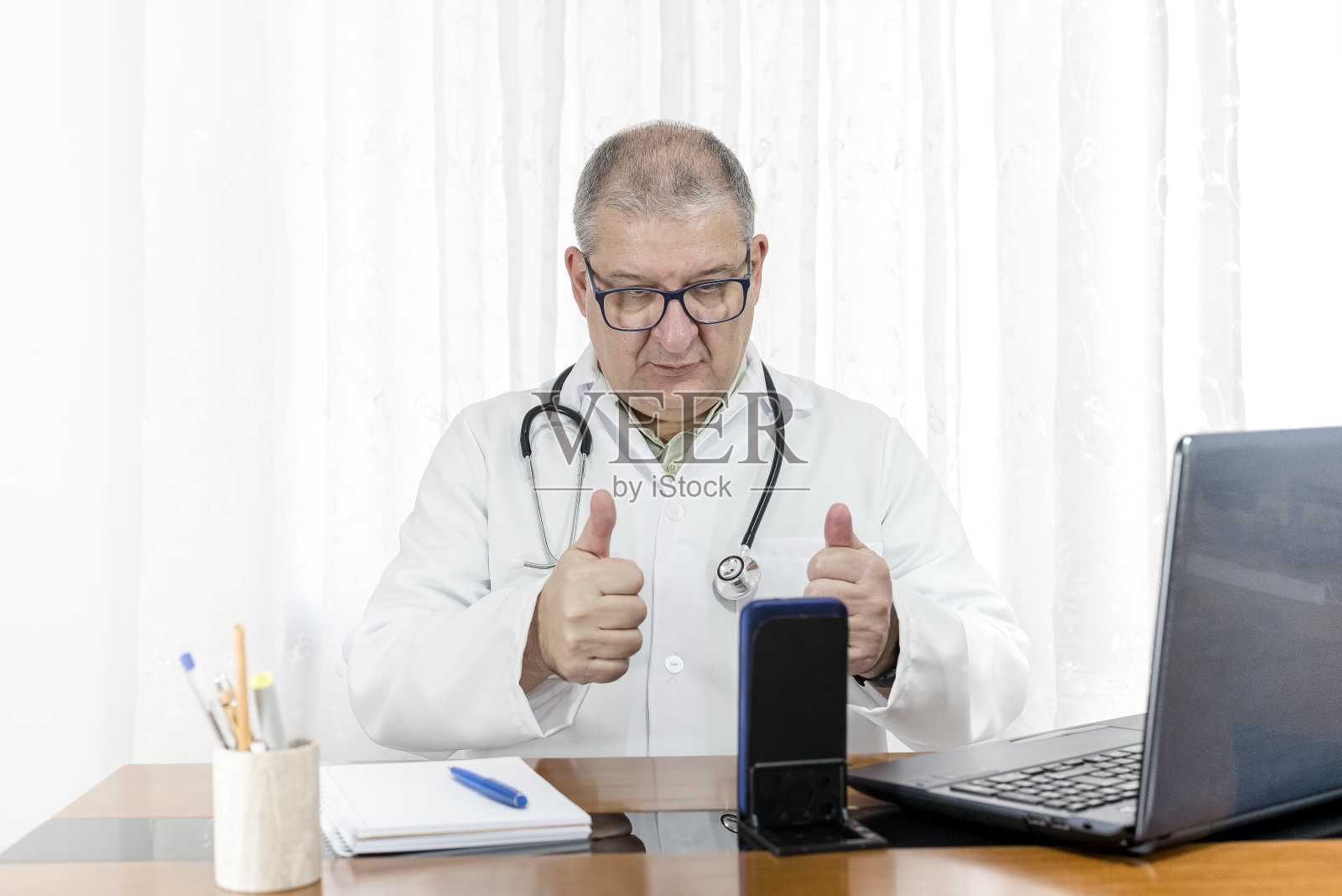 医生做虚拟护理-看着手机，双手竖起大拇指照片摄影图片