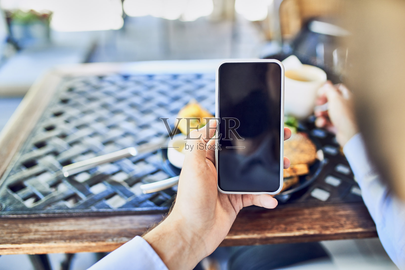 近距离拍摄的商人拿着智能手机在户外咖啡馆照片摄影图片