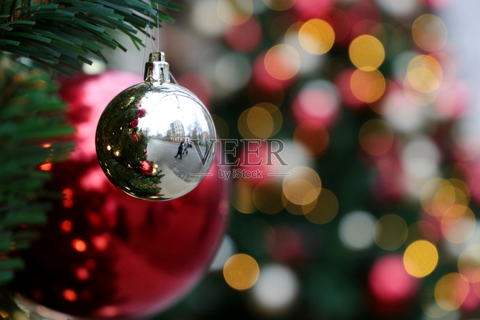 红色和银色的圣诞球放在冷杉树枝上，金色的彩灯作为节日的背景，照亮街道照片摄影图片