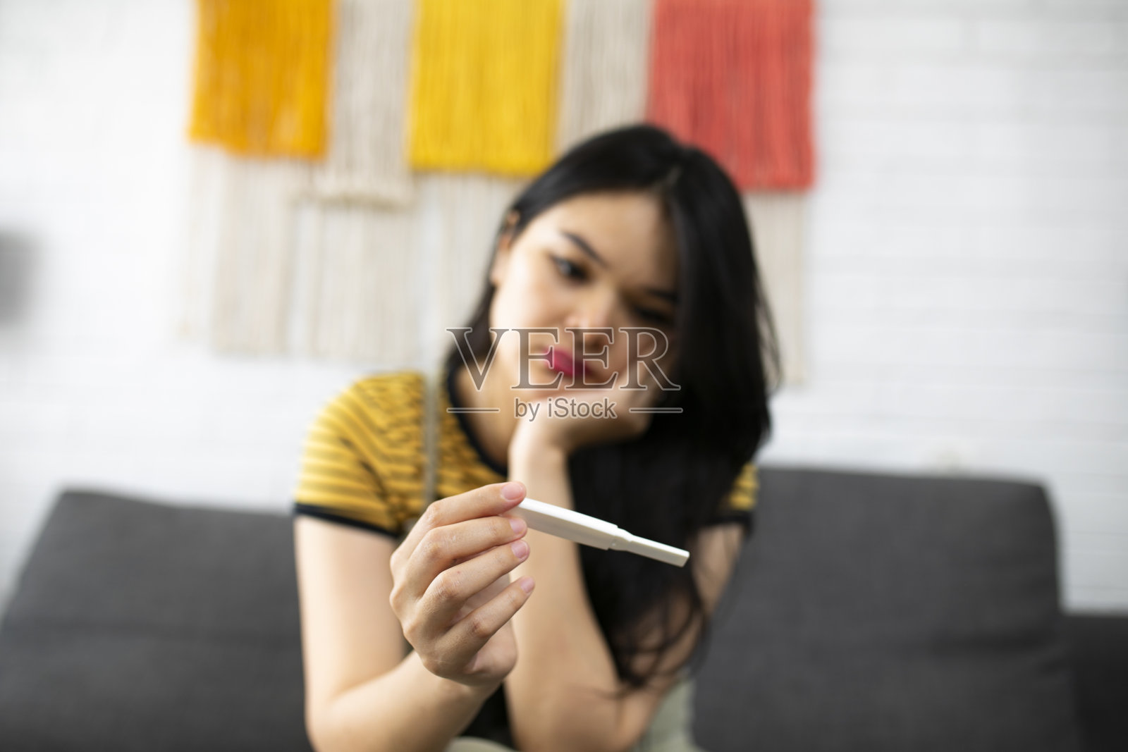 亚洲年轻女子看着怀孕测试失望的表情照片摄影图片