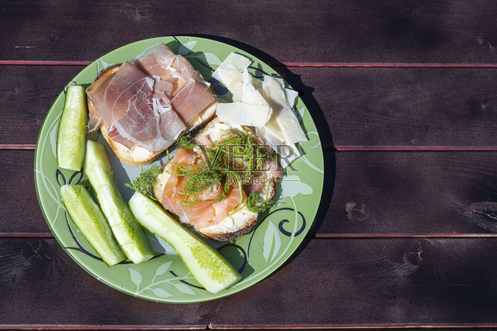 近距离观看盘子与两个三明治，奶酪和黄瓜在木制的背景。健康饮食的概念。照片摄影图片