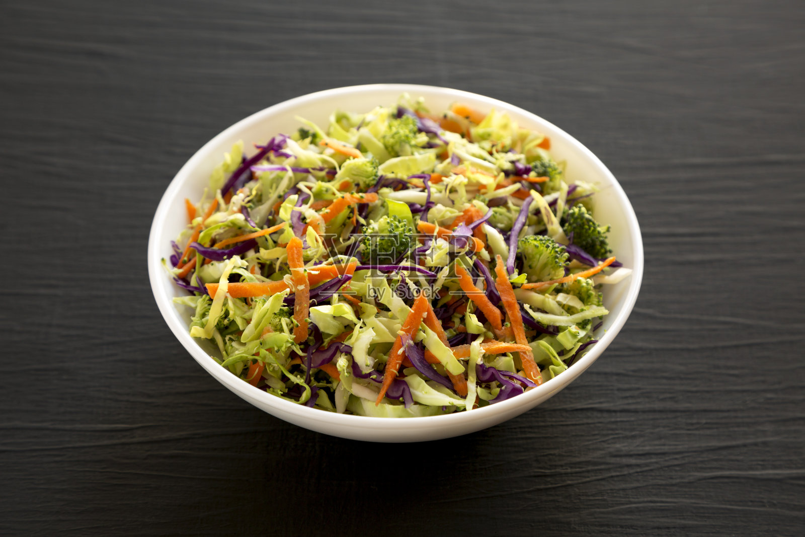 自制生西兰花丝沙拉在一个白色的碗在一个黑色的背景，侧视图。特写镜头。照片摄影图片