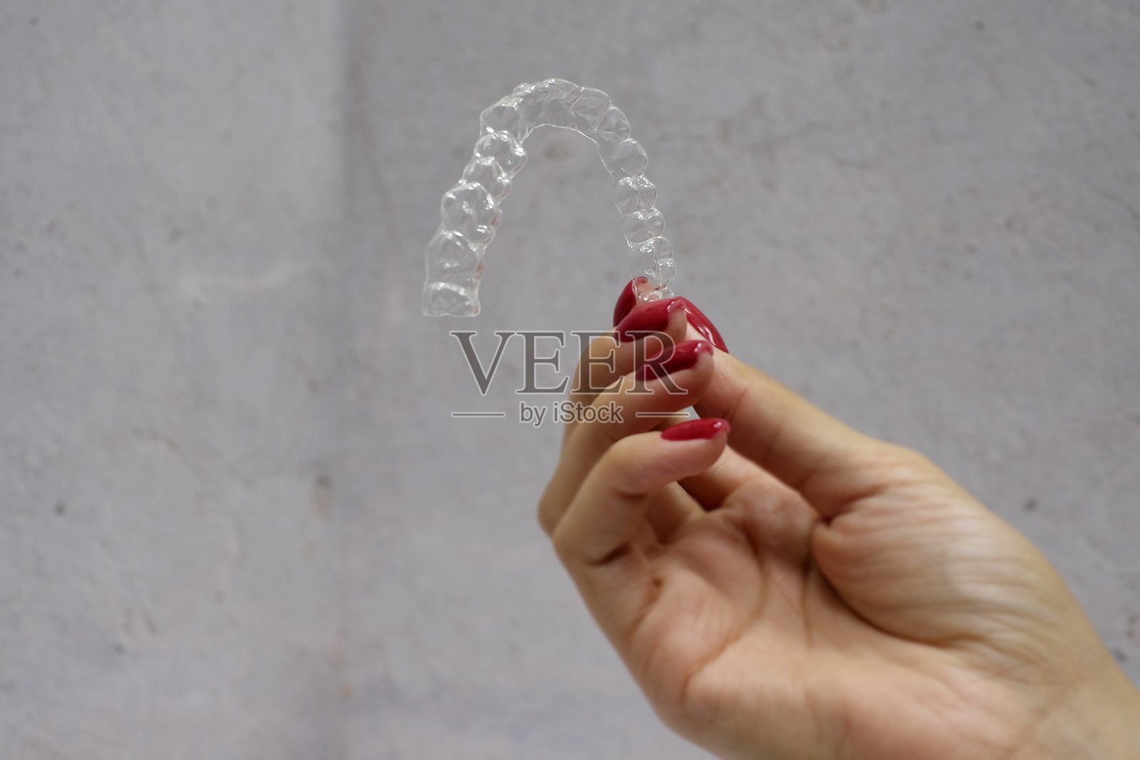 在灰色背景的女人的手握牙齿对准的特写照片摄影图片