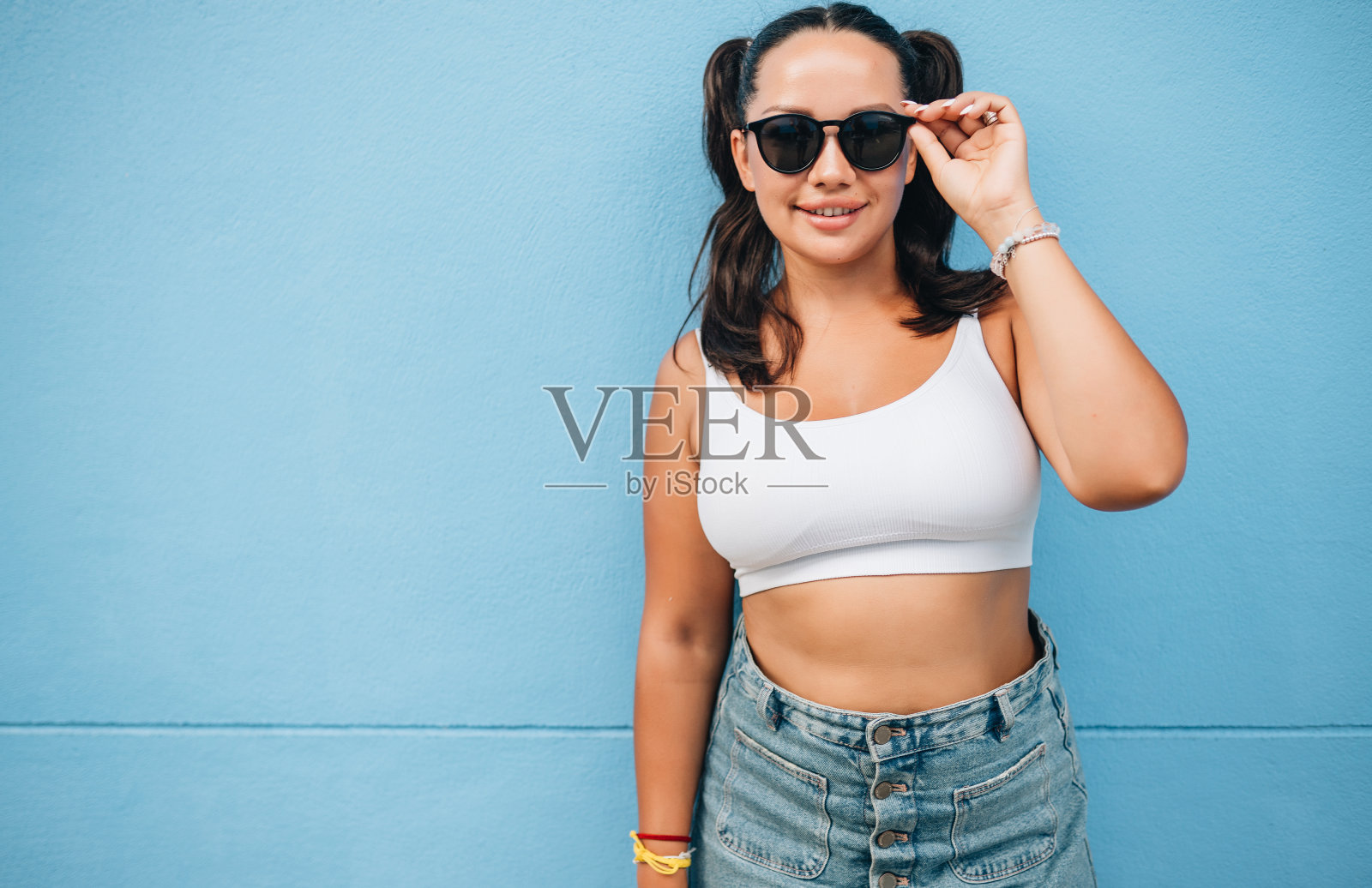 在蓝色墙壁上戴太阳镜的快乐模特肖像照片摄影图片