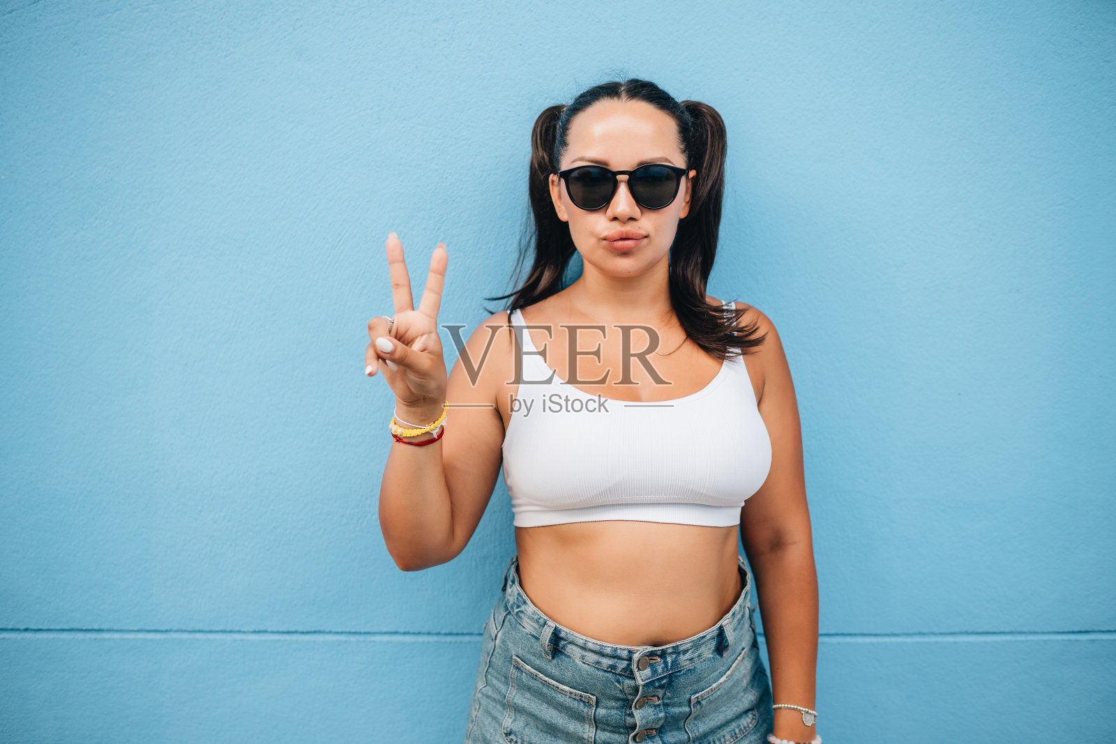 在蓝色墙壁上戴太阳镜的快乐模特肖像照片摄影图片