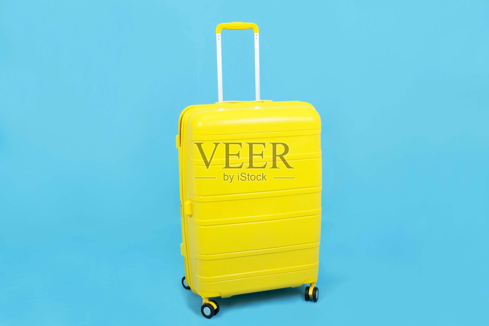 黄色行李箱或行李孤立在蓝色背景下，旅行概念照片摄影图片
