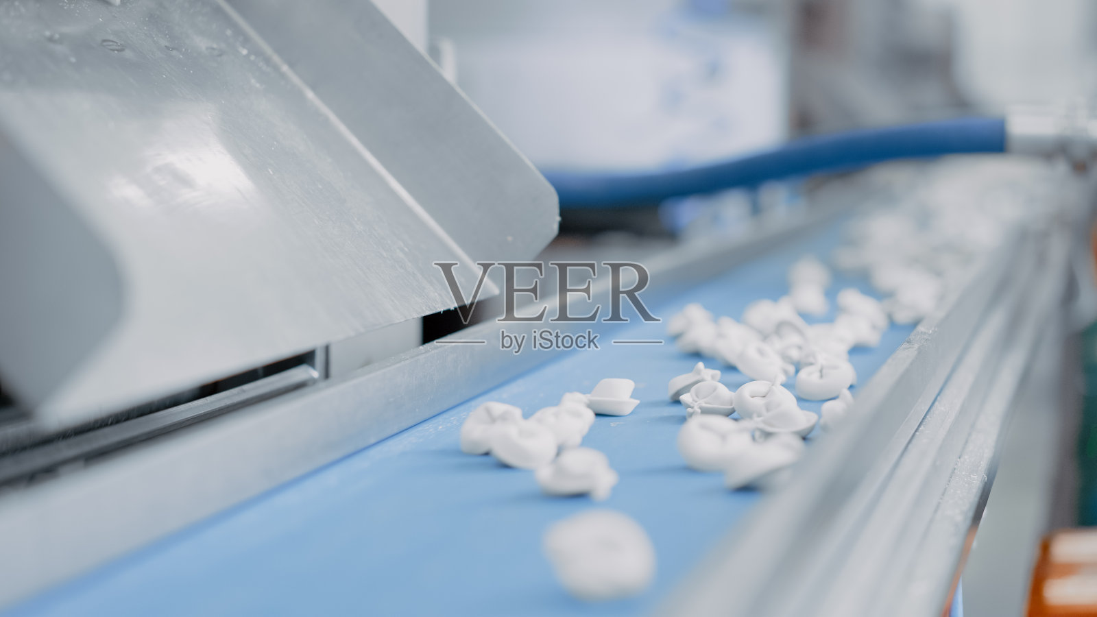 近距离拍摄的自动机器生产过程在饺子工厂。新鲜生Pelmeni落在传送带上。在食品工厂操作的工业机械。照片摄影图片