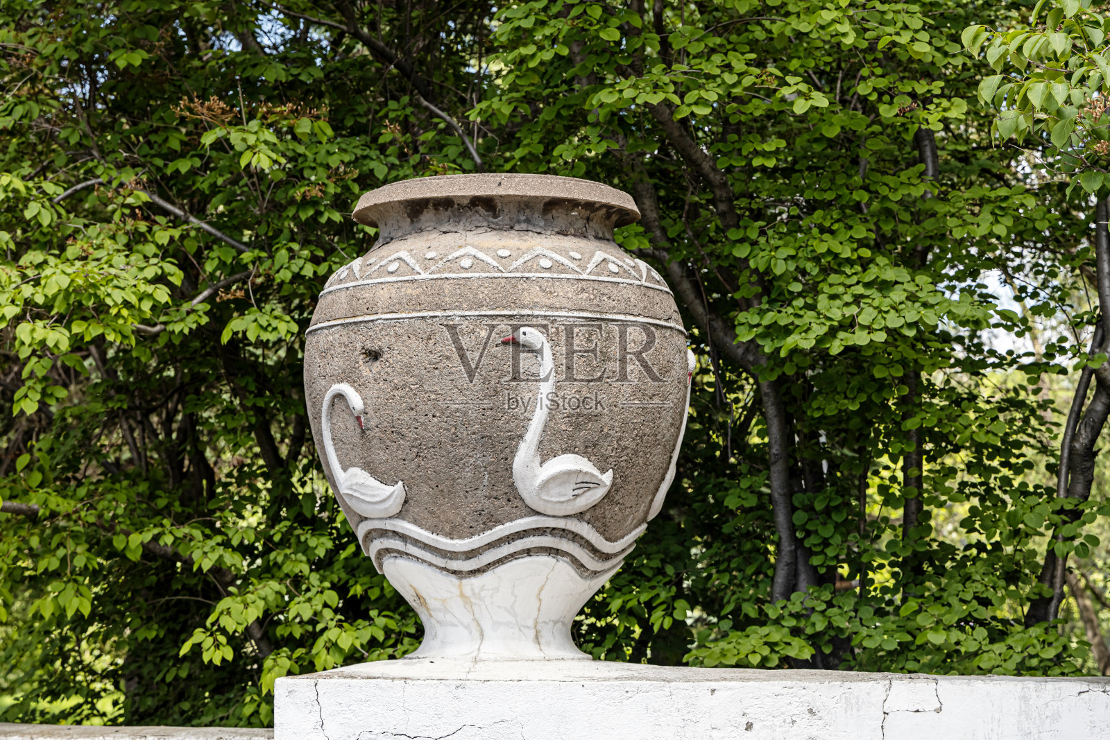 夏天，公园里有一只漂亮的灰色老石花瓶，上面画着白天鹅照片摄影图片
