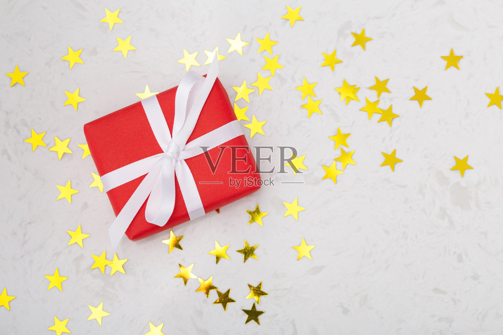 红色礼品盒，大理石桌上点缀着闪烁的金星照片摄影图片