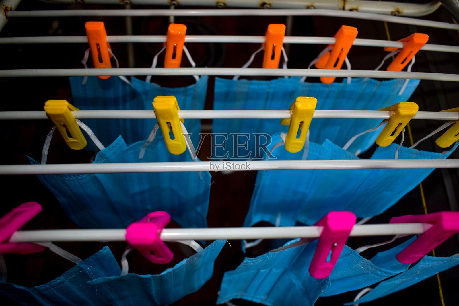 清洁后将冠状病毒口罩挂在布条上。可重复使用的蓝色口罩照片摄影图片