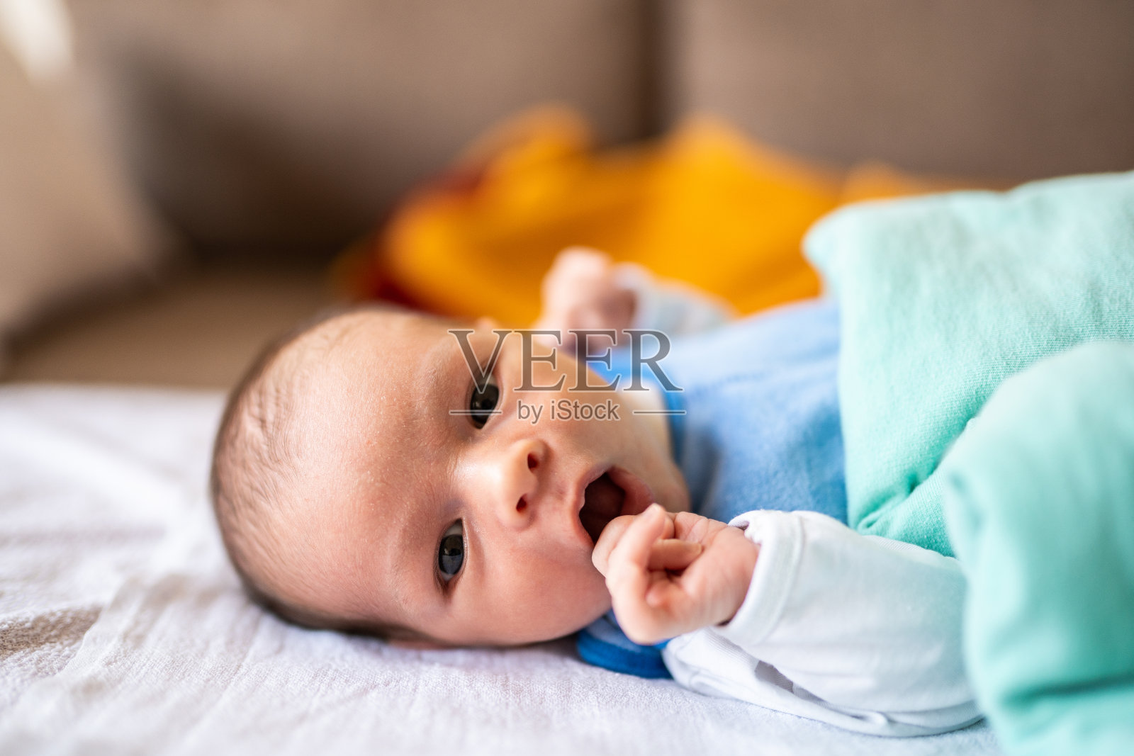 新生婴儿躺在沙发上打哈欠照片摄影图片