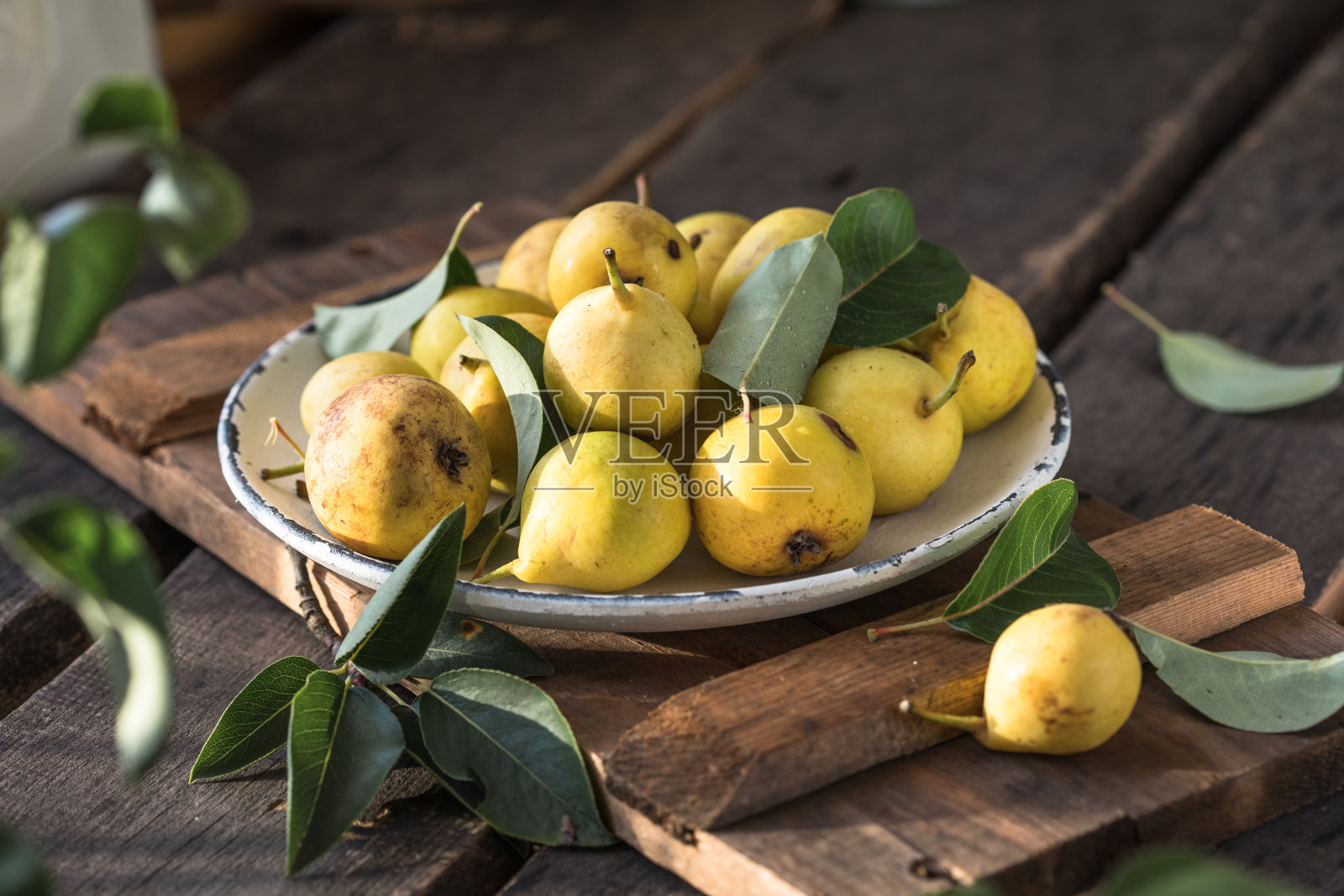 熟透的黄梨放在木背景上的盘子里照片摄影图片