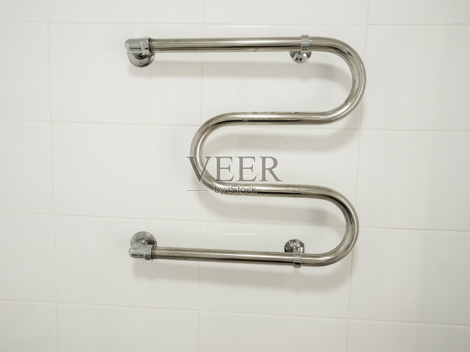 新的加热毛巾架在白色瓷砖墙上，翻新概念照片摄影图片