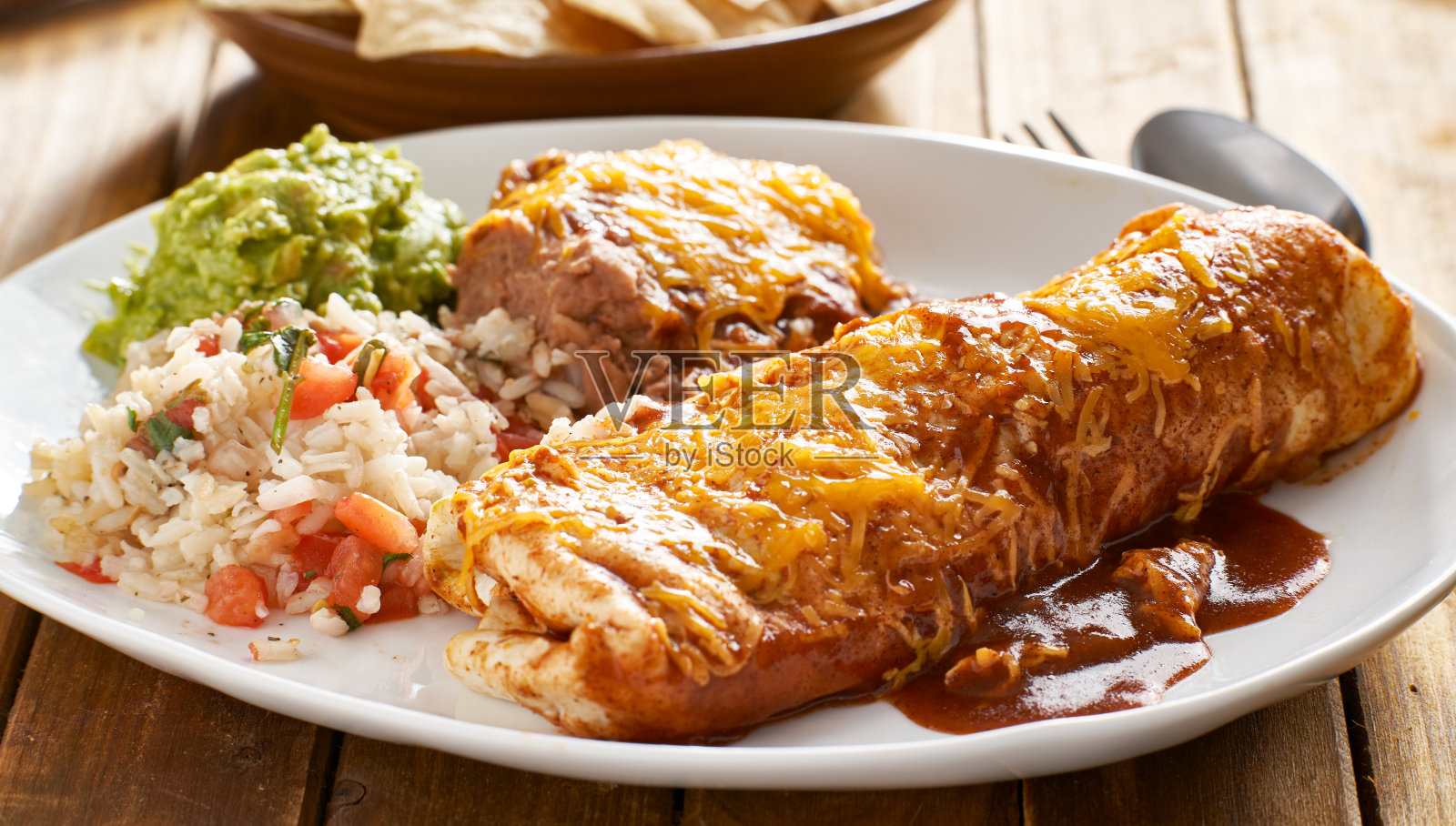 墨西哥湿玉米卷拼盘，配红玉米卷酱汁，炸豆，米饭和鳄梨酱照片摄影图片