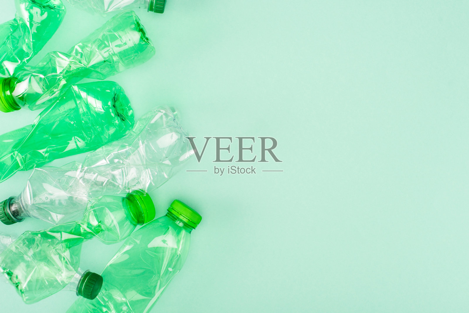 俯视图皱巴巴的塑料瓶在绿色背景上复制空间，生态概念照片摄影图片