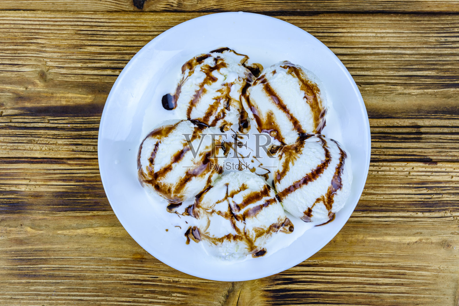 木桌上放有冰淇淋球和巧克力的盘子。俯视图照片摄影图片