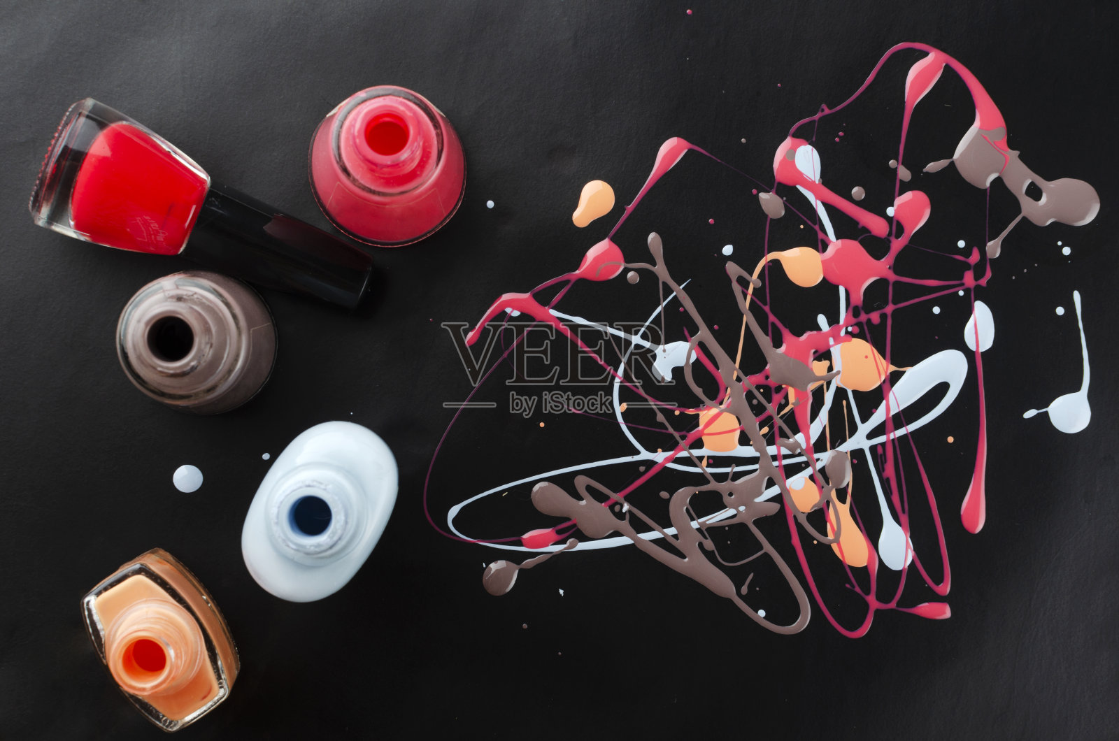 俯视图涂抹彩色的指甲油和打开的玻璃瓶在黑暗的背景照片摄影图片