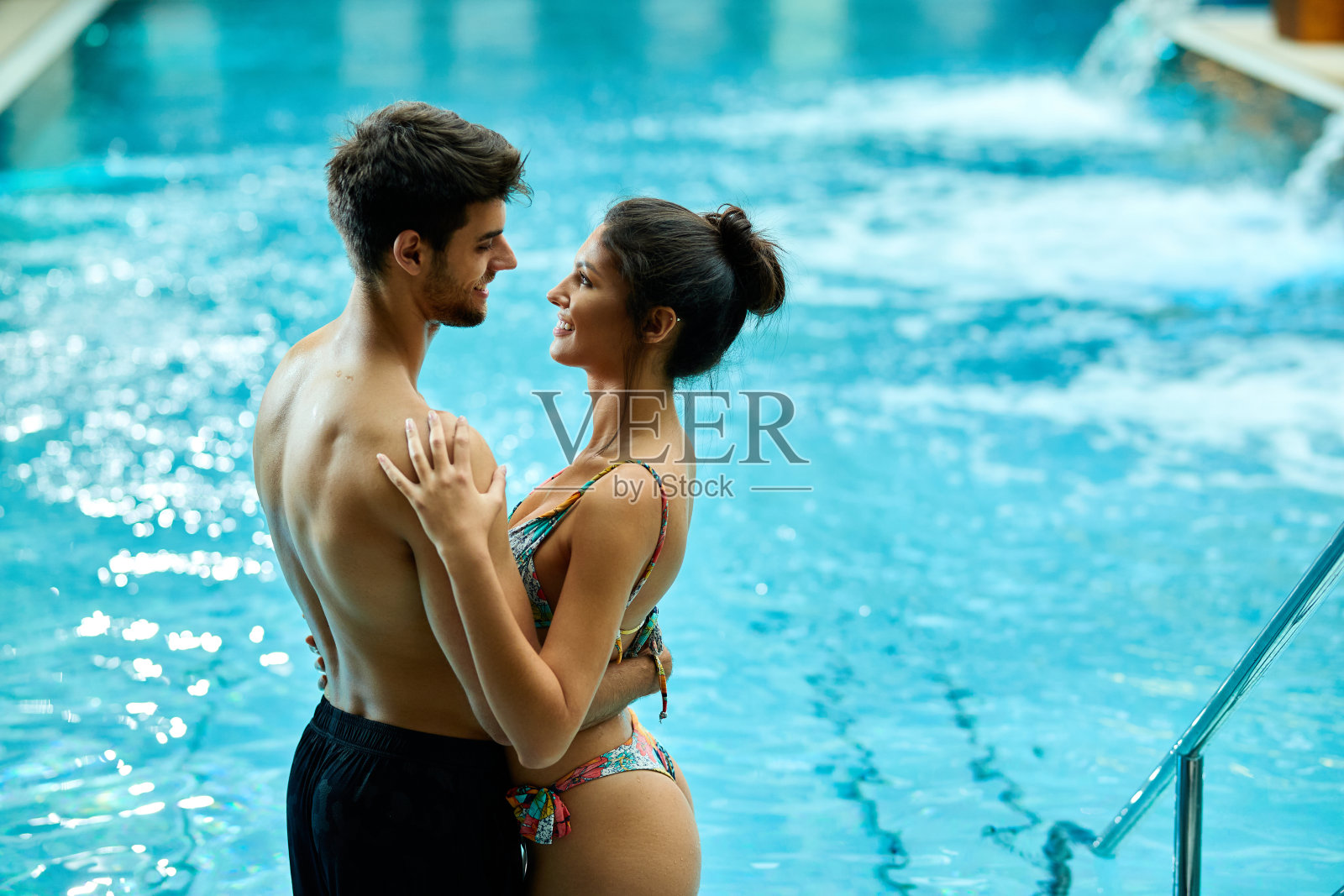 一对幸福的情侣在温泉游泳池拥抱。照片摄影图片