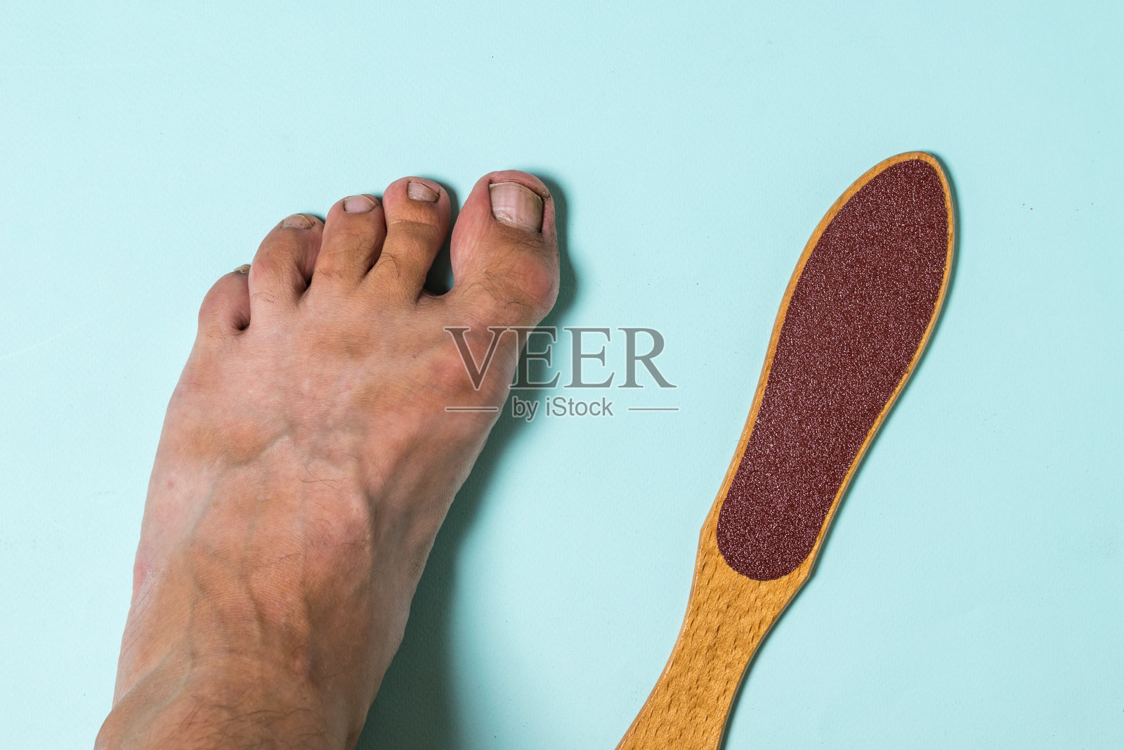 他的左脚和去除粗糙皮肤的装置。照片摄影图片