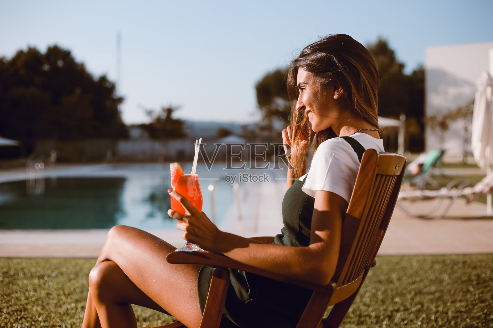 在泳池边喝鸡尾酒的美女照片摄影图片