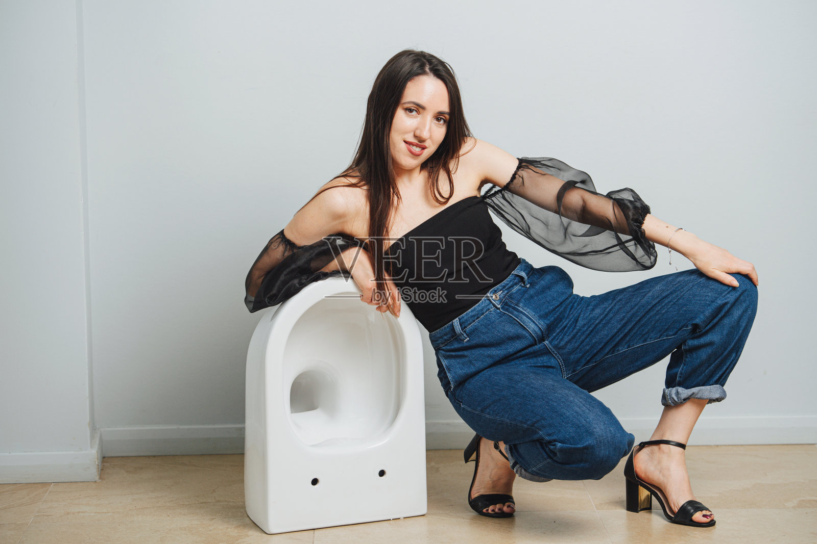 性感的年轻女子在时尚的衣服摆姿势与马桶照片摄影图片