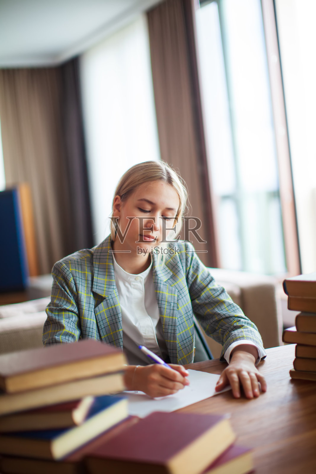 年轻可爱体贴的少女学生坐在桌子上的书在教室或图书馆。回到学校照片摄影图片