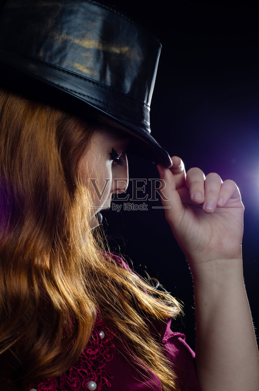 一个美丽的红头发与帽子的肖像在工作室，低调的形象，与黑色的背景。照片摄影图片