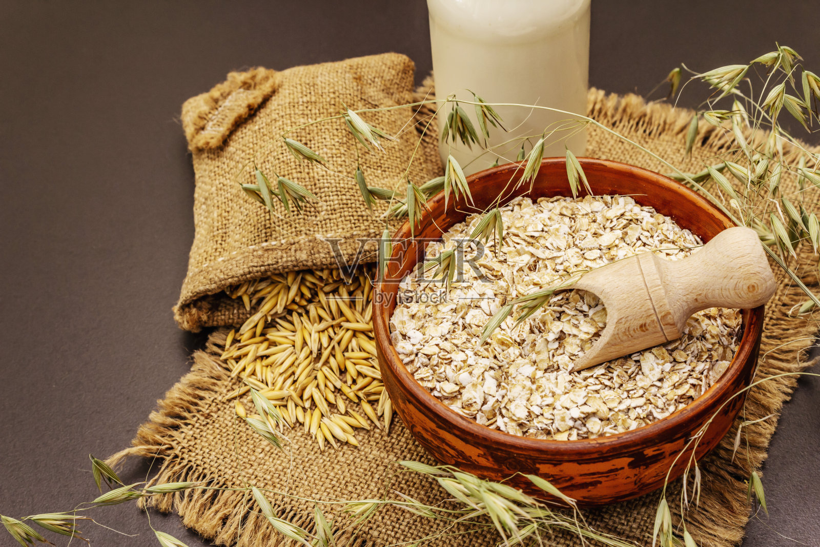 纯燕麦牛奶，非乳制品替代牛奶。将薄片放入陶瓷碗、玻璃瓶、燕麦片中烘干照片摄影图片