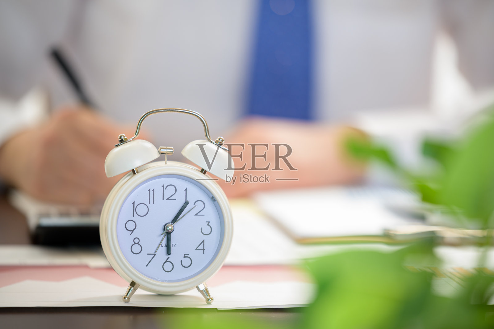 工作的商人和白色闹钟。工作时间的概念。照片摄影图片