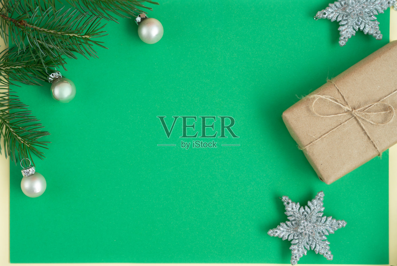 冷杉枝、圣诞球、雪花形状的圣诞玩具和一个绿色背景的礼盒。手工贺卡的概念。照片摄影图片