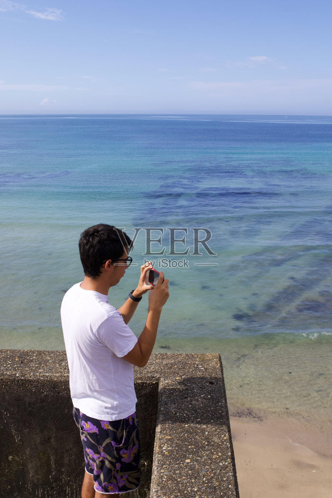 男孩用移动设备拍海洋的照片。照片摄影图片