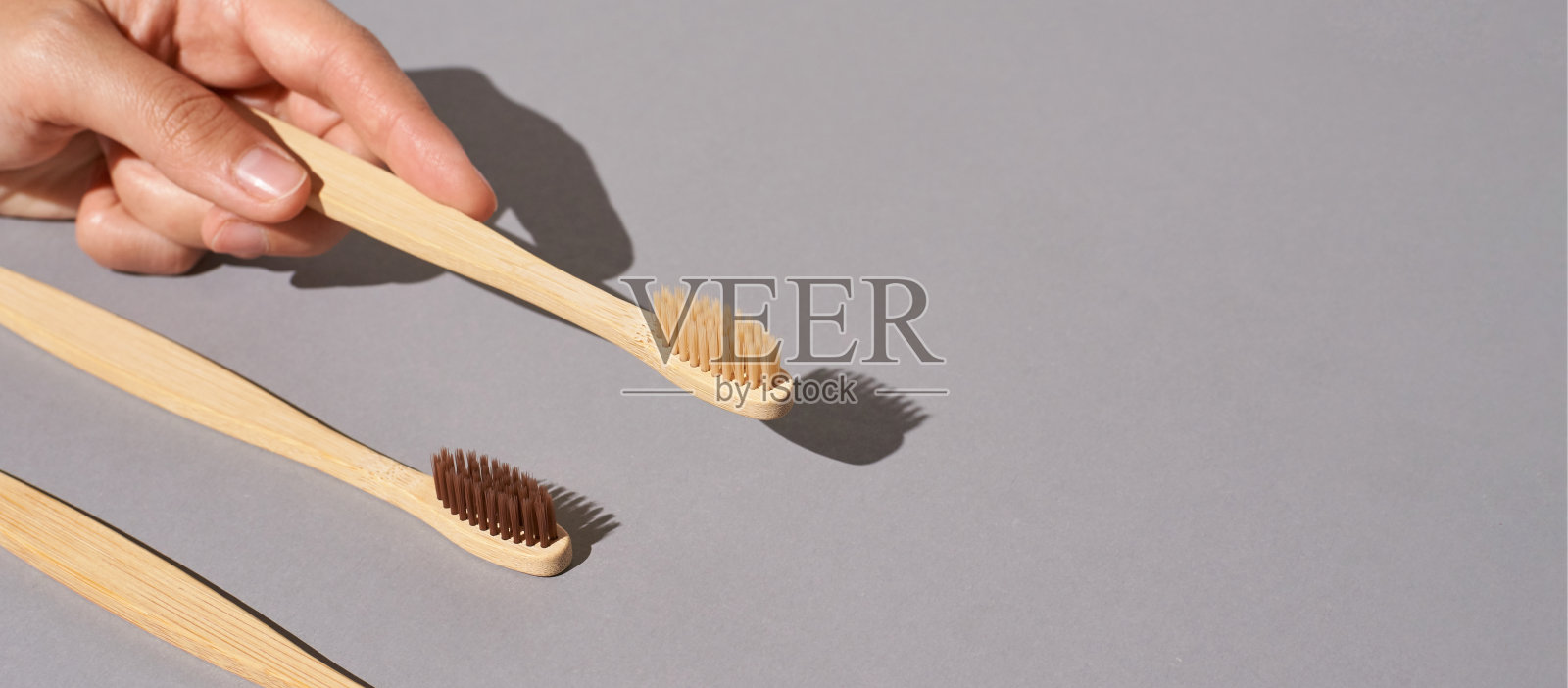手握竹制生态牙刷。灰色背景照片摄影图片