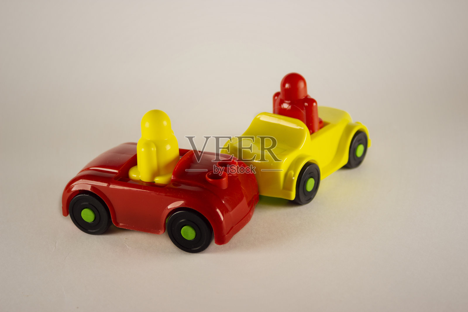 两个绝望的男人在玩具车中卷入事故，概念图像与微型和雕像在白色的背景。在白色背景上的两个玩具汽车碰撞的特写。照片摄影图片