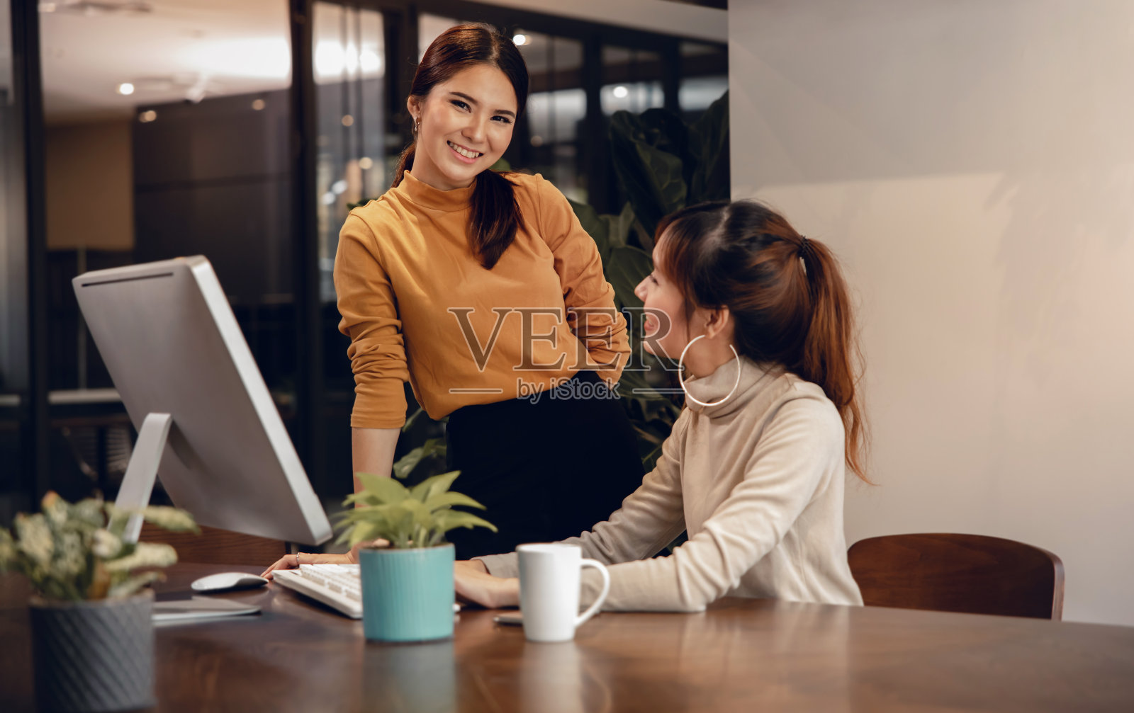 团队合作,一起工作。微笑着在现代办公室用电脑工作的两个商业女性。主模型看着相机照片摄影图片