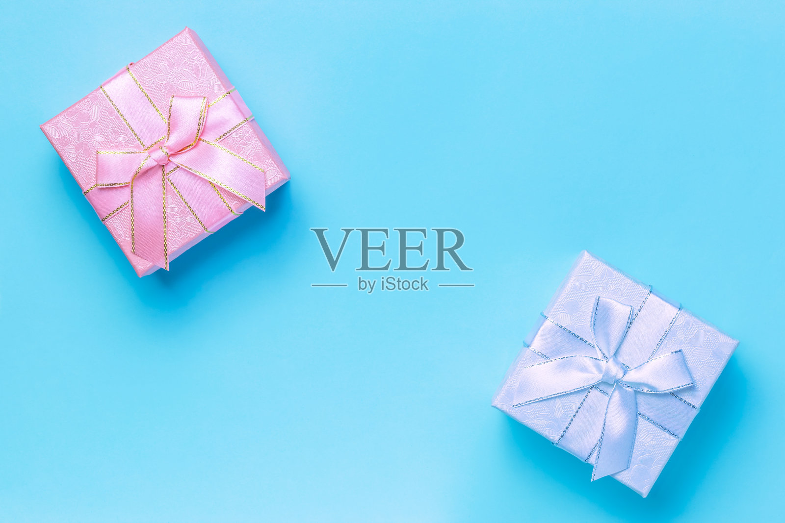 节日问候横幅，海报出售，礼物包装，美丽的粉色淡紫色与蝴蝶结从丝带为假日在蓝色背景柔和的颜色与拷贝空间俯视图，平面照片摄影图片