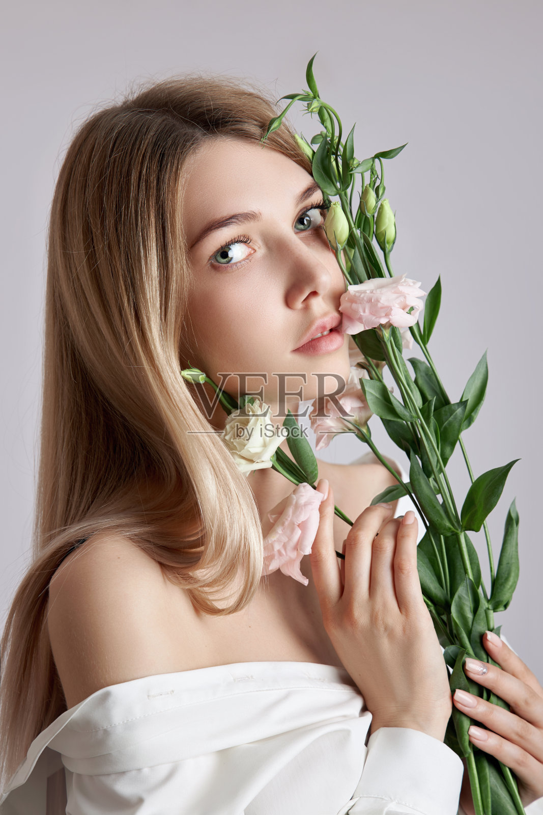 美女肖像女子与粉红色的口鼻花在她的手中。面部和身体皮肤护理的天然化妆品。穿着白衬衫的漂亮女孩照片摄影图片