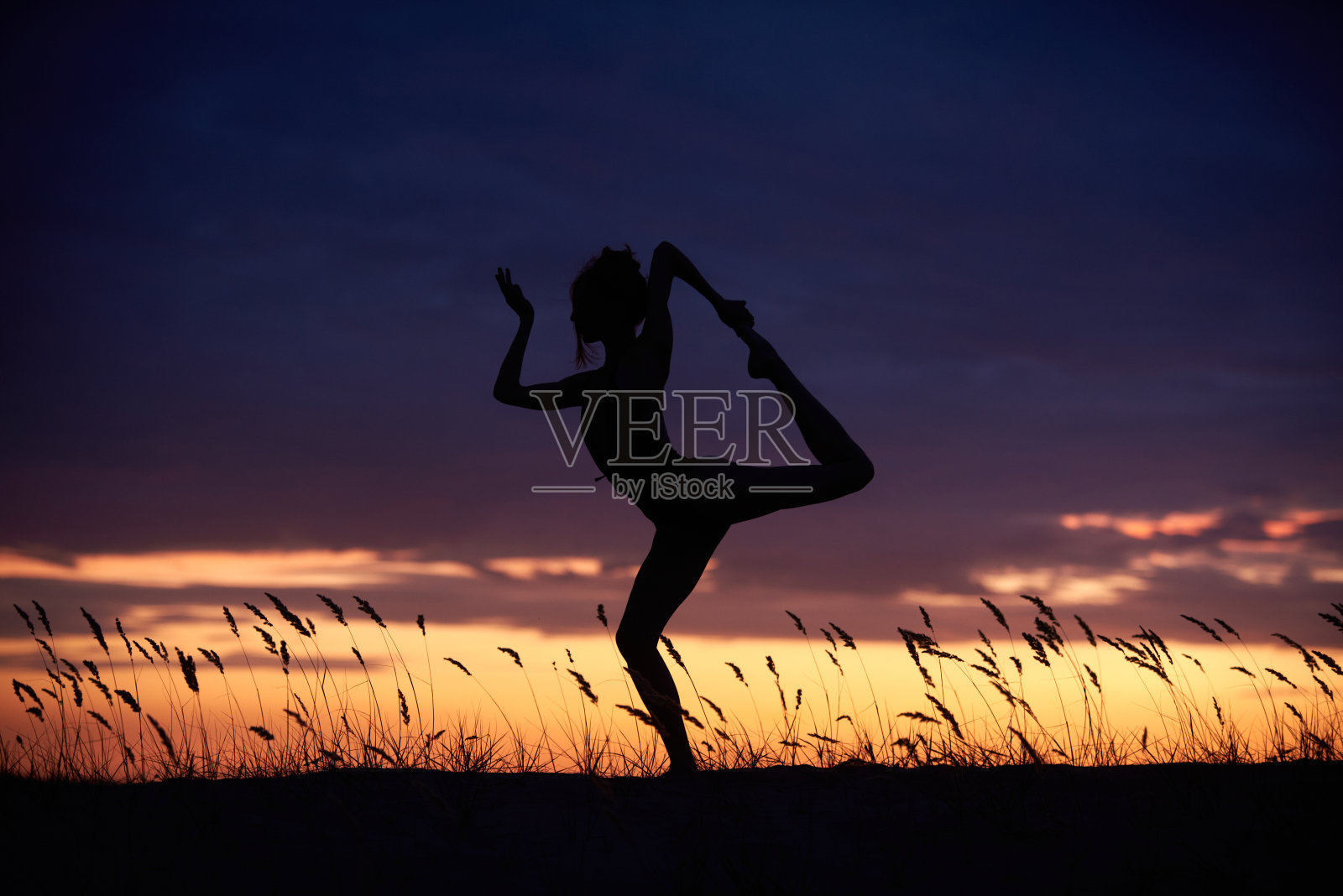 美丽的年轻女子晚上在户外练习瑜伽照片摄影图片