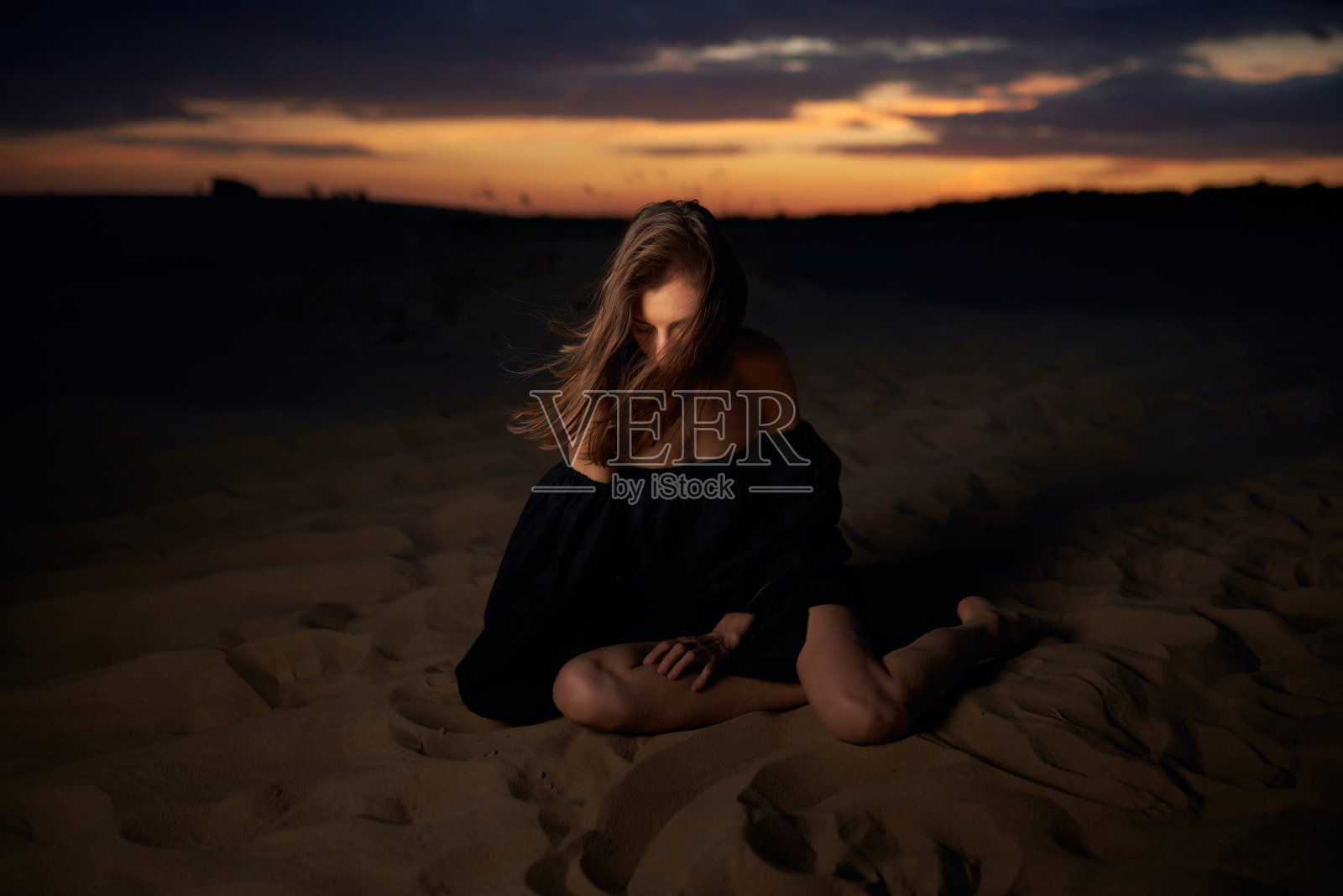 一个穿着黑色裙子在沙漠中行走的年轻女子的肖像。照片摄影图片