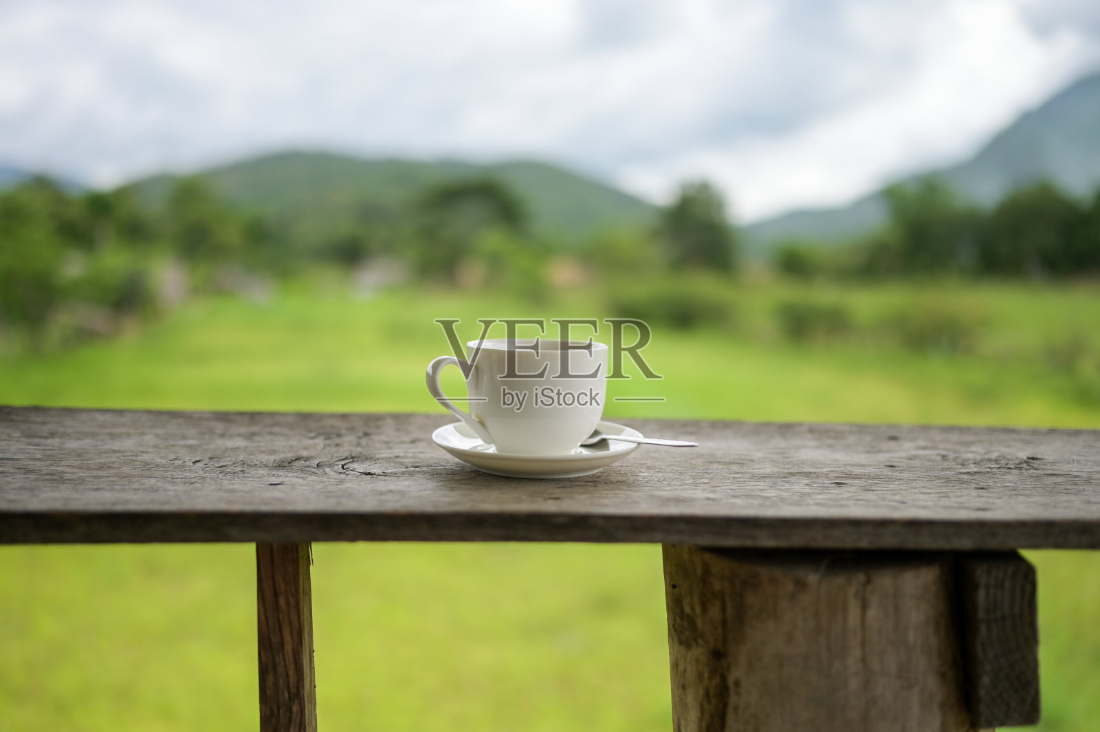 在一张木桌上喝着咖啡，俯瞰着阳光下的山川和稻田。美丽的自然背景。照片摄影图片