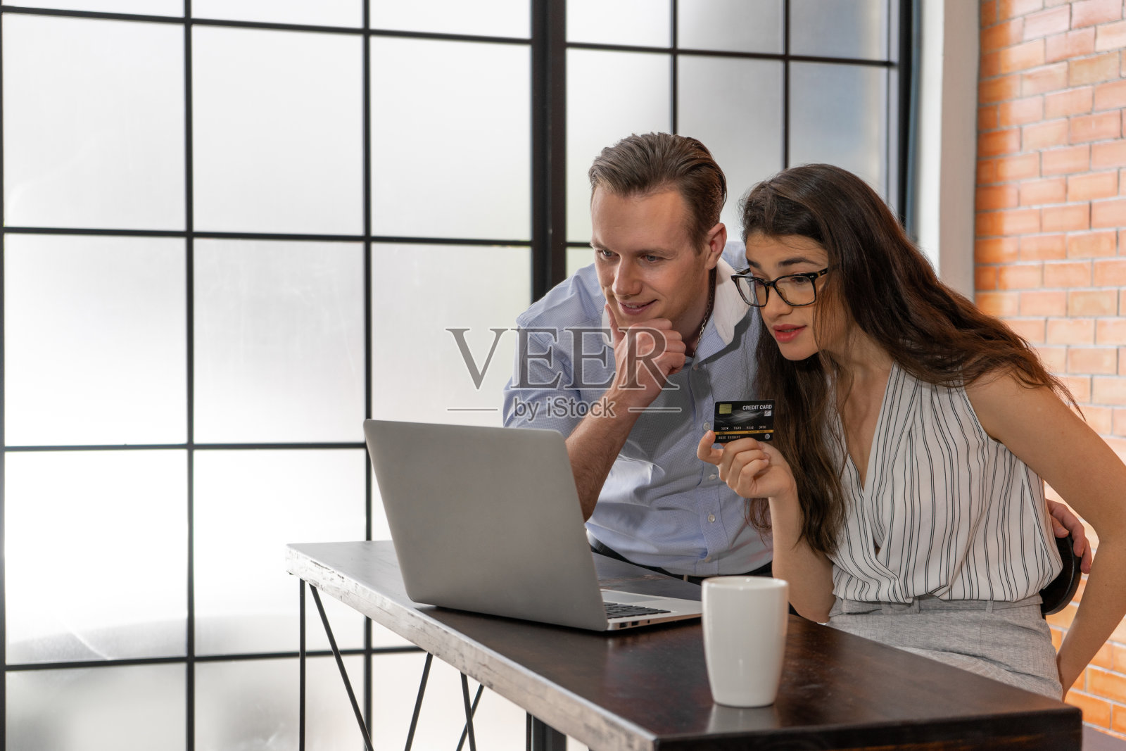 快乐的男人和女人拿着信用卡用笔记本电脑在咖啡厅网上购物照片摄影图片