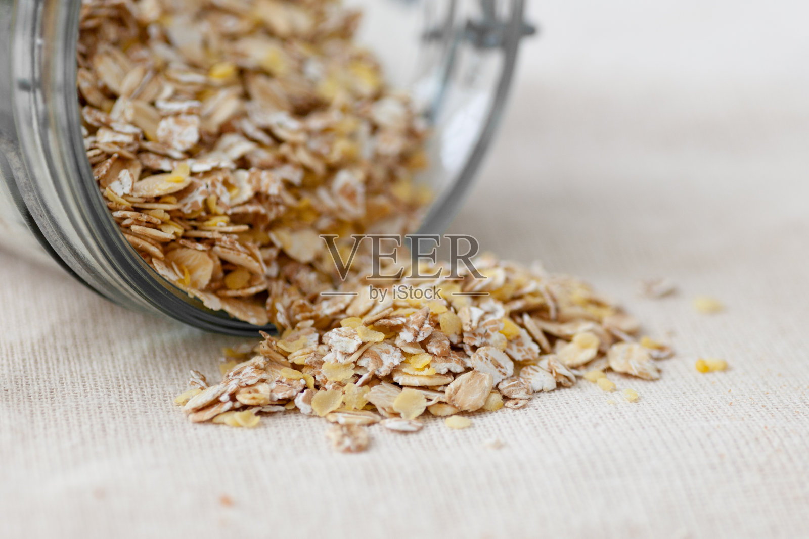 薄片，谷物洒在一张用粗麻布覆盖的木桌上，灰色的背景高音照片摄影图片