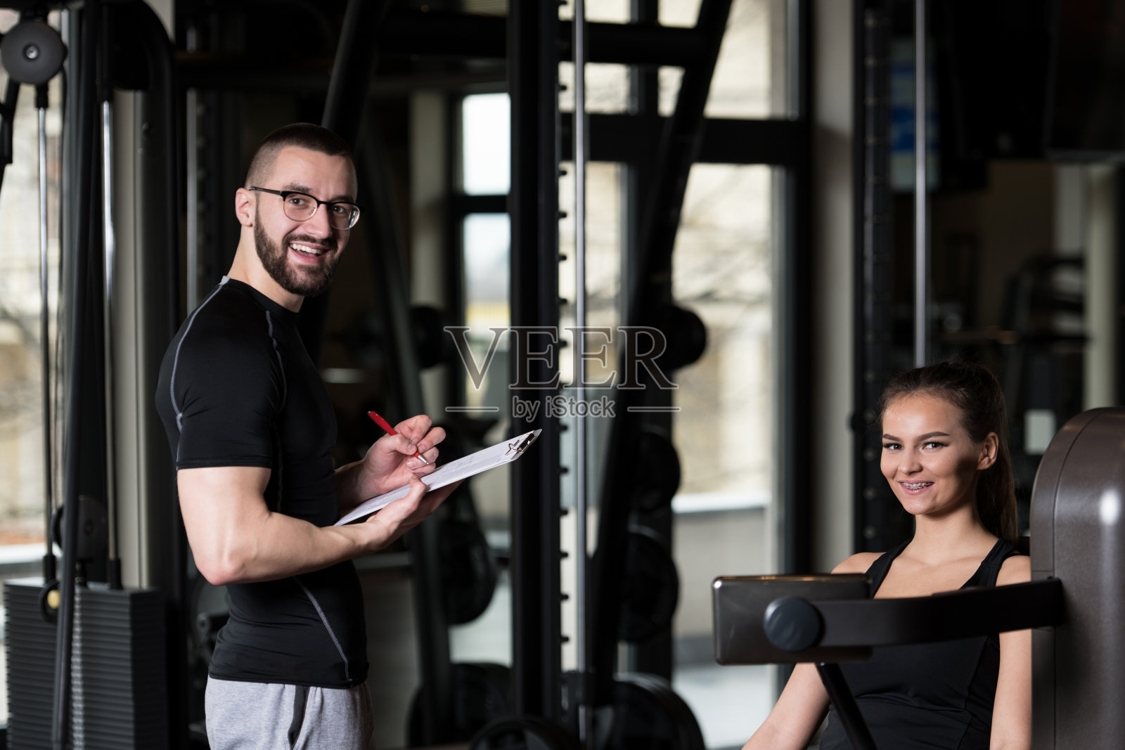 女人用私人教练在机器上训练腿照片摄影图片