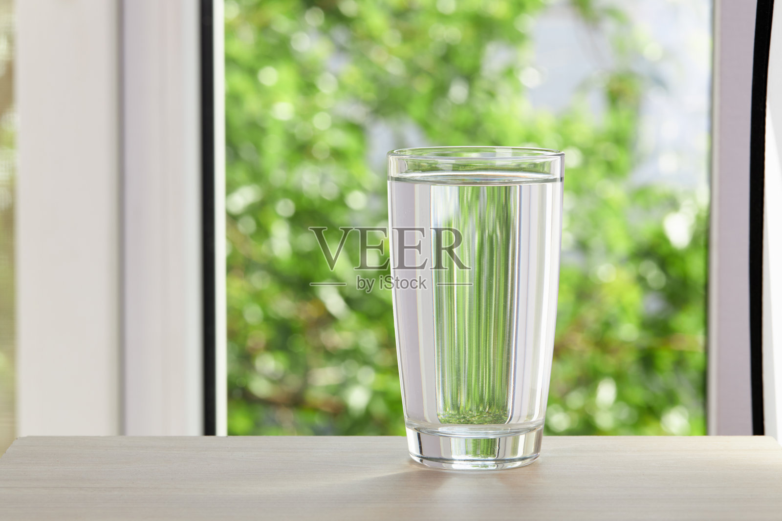 在绿色自然背景的木桌上喝水。阳光明媚的一天。影棚拍摄。生活方式的概念照片摄影图片