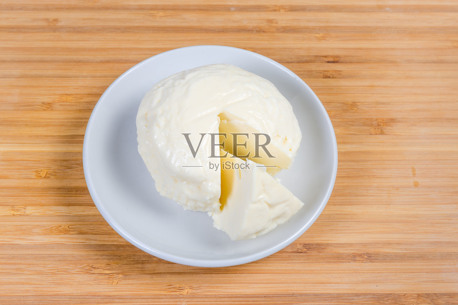 将软干酪球放在木盘上，切开一部分照片摄影图片