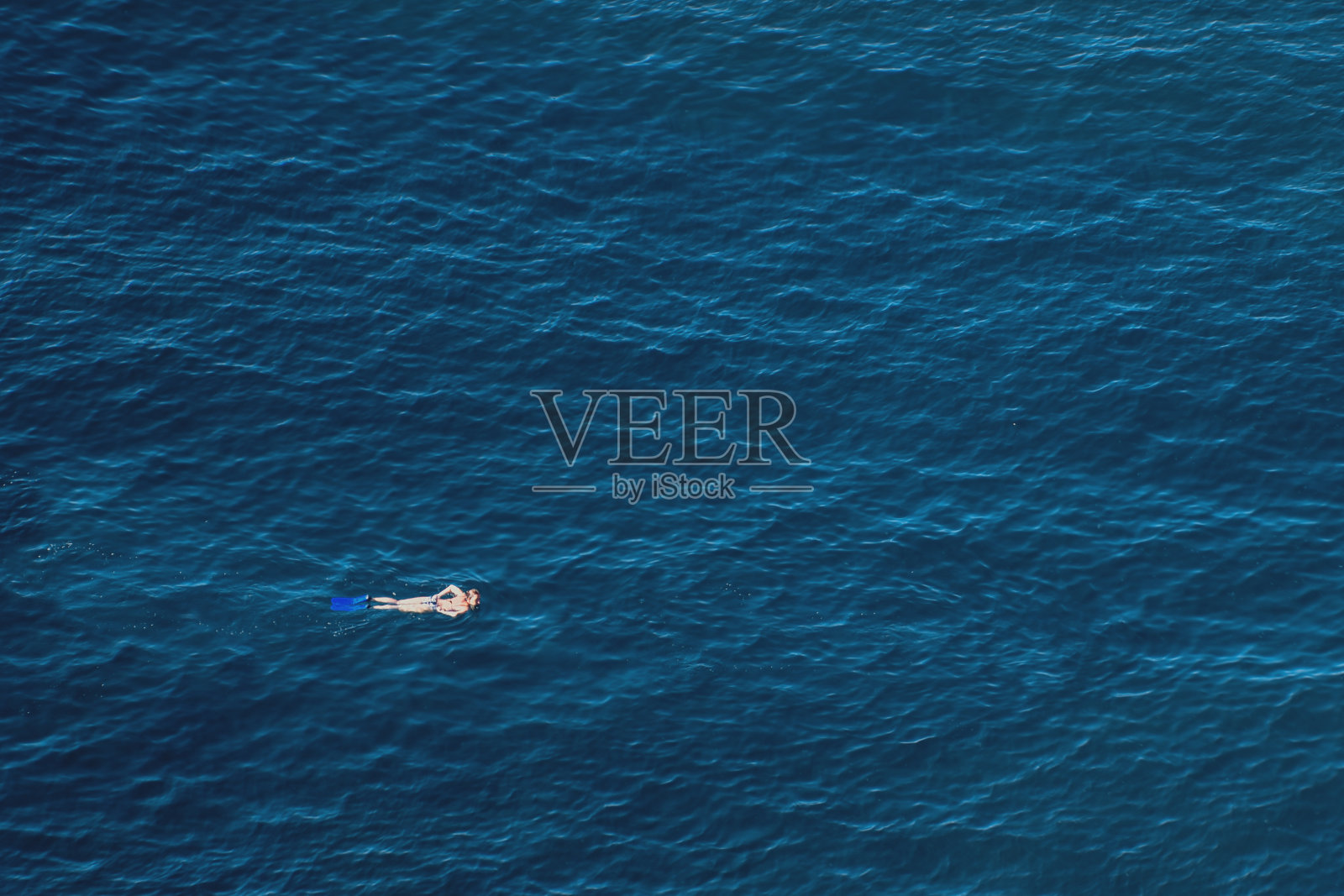 一个年轻人穿着脚蹼和面具在平静的大海中游泳照片摄影图片